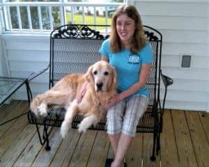 Kolby sitting outside on porch furniture, Sunny lying next to her.