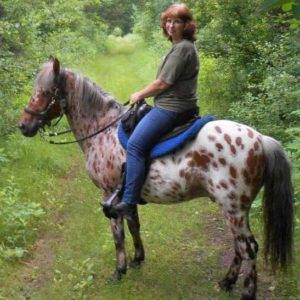 Veleda sitting astride a brown and white spotted horse.