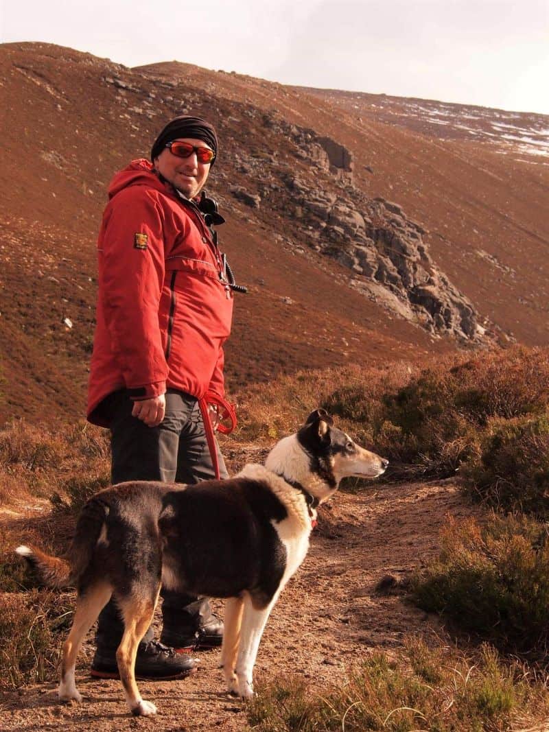 Finn and Stephen stand side by side on a mountainside in the golden light of a setting sun