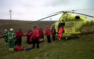 A group of rescuers gather around a helicopter