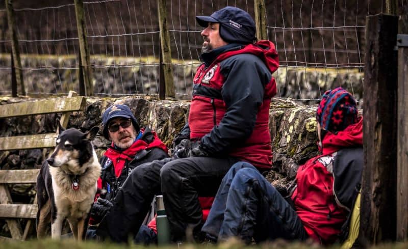 Stephen, Finn, and other rescue members sit outside before a fence