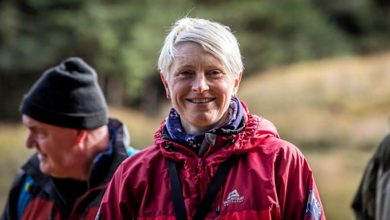 A pretty, white-haired woman stares directly into the camera with a strong smile