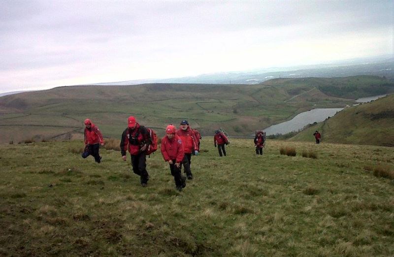 A group of rescuers climb a hill