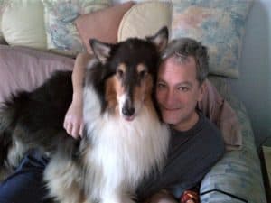 Pepsi and Dad sit together on the couch. Dad has his arm thrown around Pepsi's neck