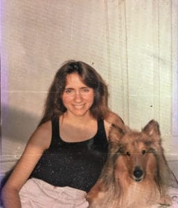 a young woman in a black tank top and skirt poses beside a sable and white Collie, photo from circa 80s-90s