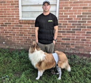 A sable and white Collie wearing a Lick Sleeve stands outside with a man wearing a black Lick Sleeve t-shirt